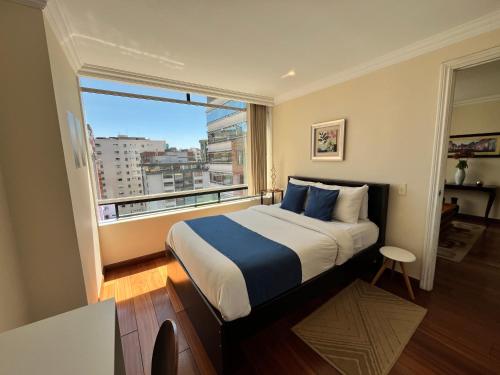 a bedroom with a bed and a large window at BlueZone Apartments in Quito