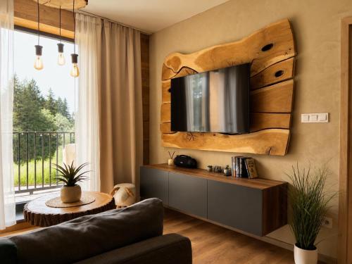 a living room with a couch and a tv on the wall at Apartmán Dubový důl in Černý Dŭl