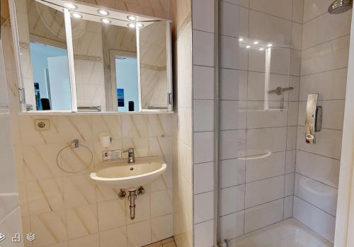 a white bathroom with a sink and a shower at Reiterpension Marlie in Scharbeutz