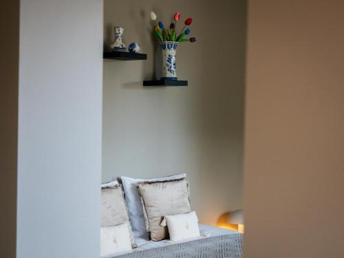 a white couch with a vase of flowers on a wall at Tip !!! Appartementen Leonardus in Valkenburg