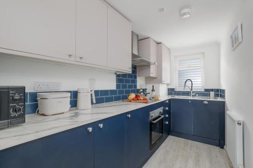 a blue and white kitchen with blue cabinets at Driftwood by Grandeur Property in Bournemouth