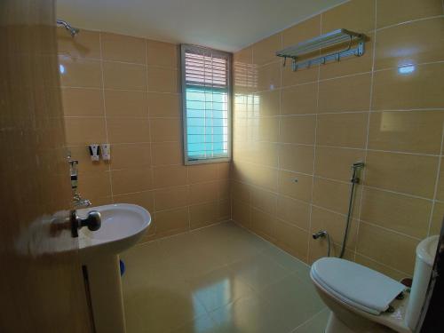 a bathroom with a toilet and a sink at Cox West Inn in Cox's Bazar