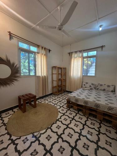 a bedroom with a bed and a table and windows at Brown & White House in Paje