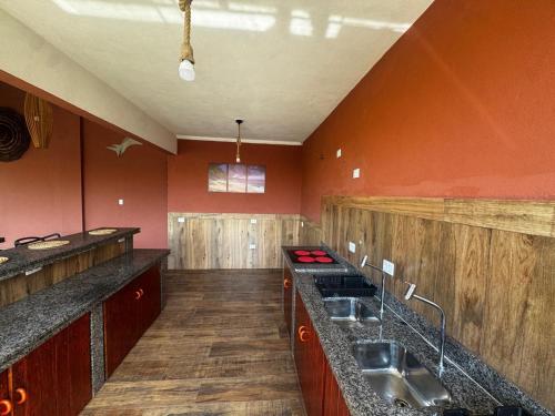 a large kitchen with red walls and wooden floors at Recanto Praia do Sargi in Uruçuca