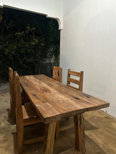 a wooden table and chairs sitting next to a wall at Brown & White House in Paje