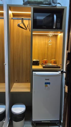 a small kitchen with a microwave and a refrigerator at Casa de São Jorge in Pirenópolis