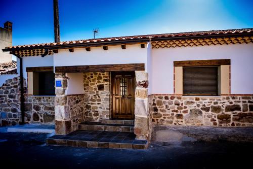 a stone house with a wooden door and stairs at El Rincón del Silencio in Entrala