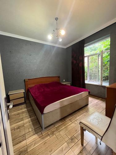 ein Schlafzimmer mit einem großen Bett und einer roten Decke in der Unterkunft Ромашка in Uçgün