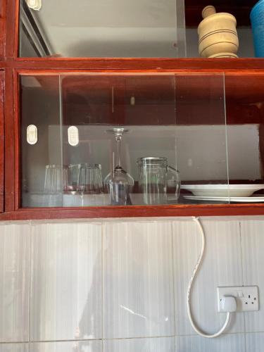a glass cabinet with dishes and glasses in it at Casa Bnb kisumu in Kisumu