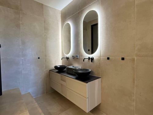 a bathroom with two sinks and two mirrors at Filon Ktima Beachfront Upscale Villa in Karavádhos