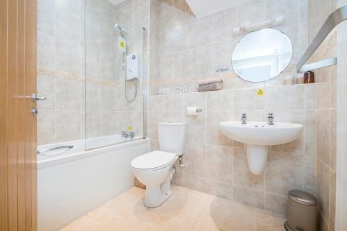 a bathroom with a toilet and a sink and a mirror at Ramsey View in Solva