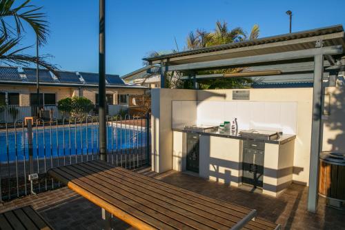 a patio with a bench and a kitchen and a pool at Nesuto Geraldton in Geraldton