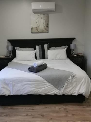 a bedroom with a large white bed with a black headboard at Feathers Guest House in Welkom