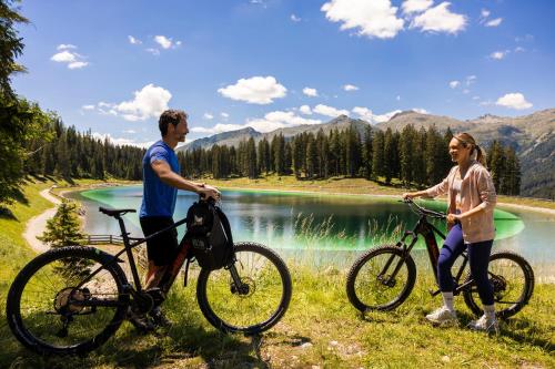 a man and a woman standing with bikes in front of a lake at Hotel Splendid in Madonna di Campiglio