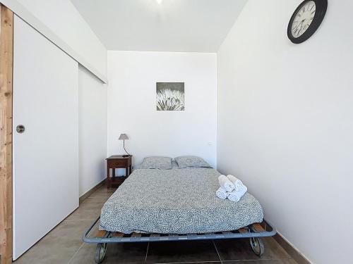 a bed in a white room with a clock on the wall at Studio avec terrasse en rez de chaussée in Lapalme
