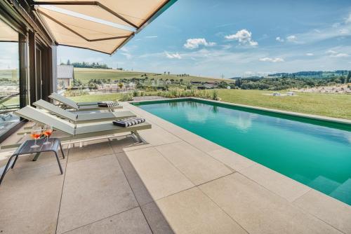 a swimming pool with a bench and an umbrella at BlackForestChillOut - Pool - Garten - BBQ - Sauna in Stühlingen