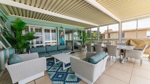 an outdoor patio with tables and chairs and windows at 62 Camarque Umdloti Beachfront in Umdloti