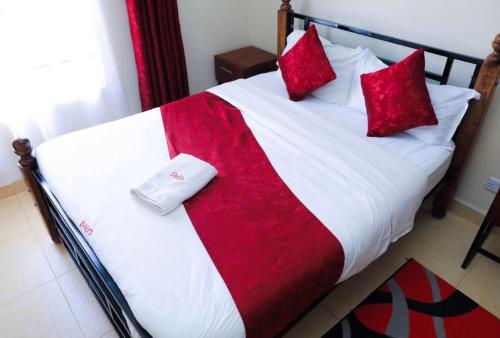 a bed with red and white sheets and red pillows at 3 Bedrooms in Eldoret in Eldoret