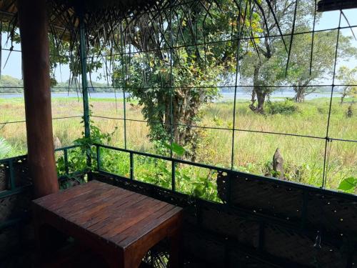 a porch with a wooden bench and a view of a field at Lake Cabin in Polonnaruwa