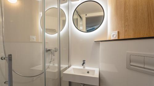 a bathroom with a shower and a sink and a mirror at Premiere Classe Bayonne in Bayonne