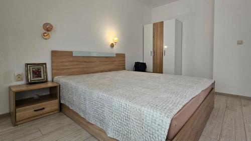 a bedroom with a large bed and a night stand at Душковата къща in Chekhlare