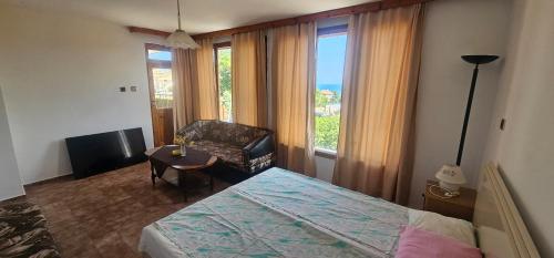 a bedroom with a bed and a chair and a window at Атлас in Byala