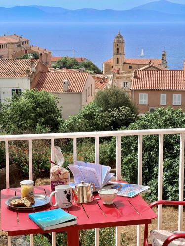 ein roter Tisch mit Essen auf einem Balkon in der Unterkunft Solacargese-Le Jardin d'Irène-Vue panoramique exceptionnelle sur la Méditerranée in Cargèse