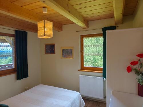 a bedroom with a white bed and two windows at Kocurzonka Apartamenty in Jaworzynka