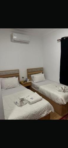 a room with two beds with towels on them at Phoenix Pyramids Inn in Banī Ghālib