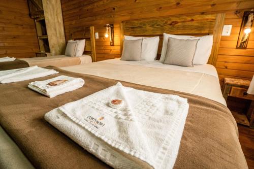 a bedroom with two beds with towels on them at Pousada Costaneira in Cambará