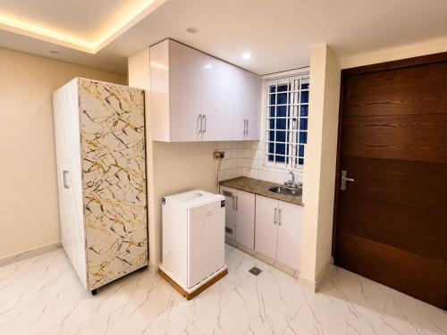 a kitchen with a refrigerator next to a door at Motorway Majesty Heights - Near Islamabad International Airport and Motorway in Islamabad