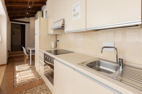 a kitchen with white cabinets and a sink at BolognaRoomscom - Santo Stefano Apartments in Bologna