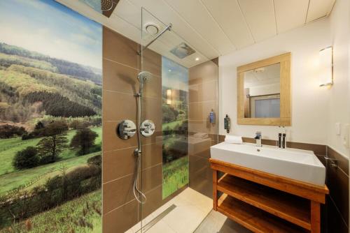 a bathroom with a sink and a shower with a painting at Center Parcs Les Ardennes in Vielsalm