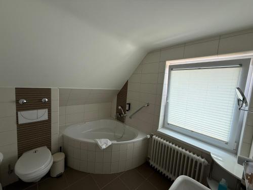 a bathroom with a tub and a toilet and a window at Hotel Markgräfler Hof in Badenweiler