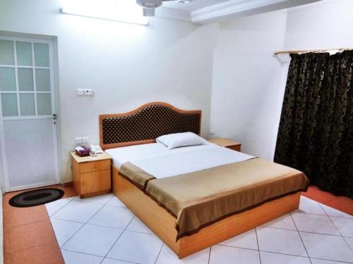 Schlafzimmer mit einem großen Bett mit einem Kopfteil aus Holz in der Unterkunft Sun City Hotel in Muscat