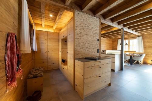 a room with wooden walls and a kitchen with a table at Chalet Brisi - Luxury & Bergblick in Wildhaus