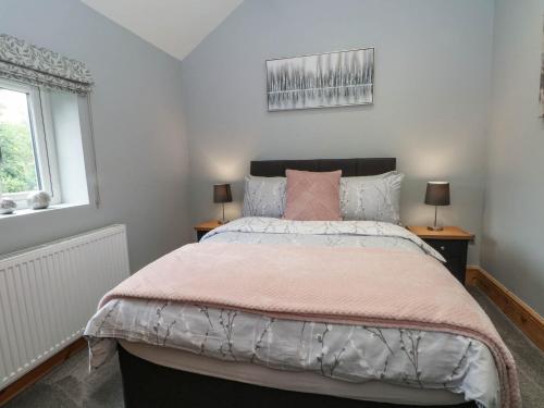 a bedroom with a large bed with a pink comforter at Barn 2 in Sandbach