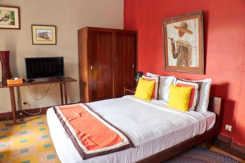 a bedroom with a bed with yellow pillows and a television at Hotel Joffre in Toamasina