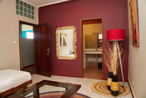 a living room with a red wall with a mirror at Hotel Joffre in Toamasina