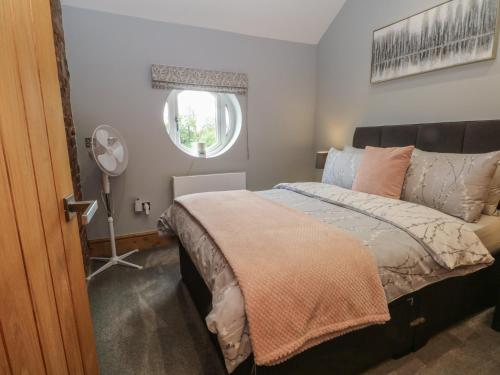 a bedroom with a bed and a window and a fan at Barn 1 in Sandbach