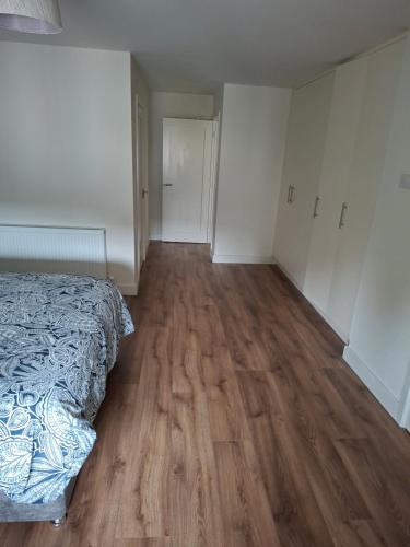 an empty bedroom with a bed and a wooden floor at Spacious ensuite bedroom in Kiltiernan