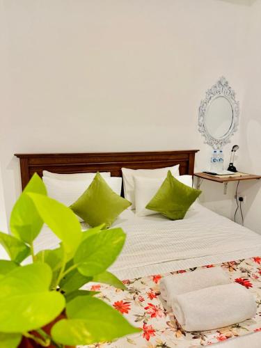 a bedroom with a bed with green and white pillows at Sea Breeze Guest House Negombo Beach & Airport in Negombo