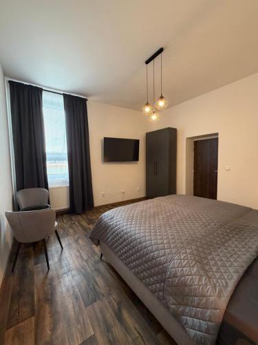 a bedroom with a bed and a chair and a television at Apartmán Pardubice 4 in Pardubice