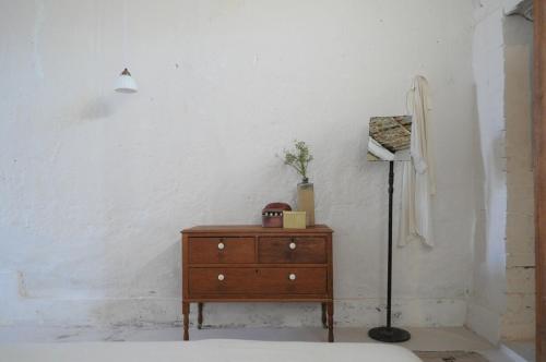 a bedroom with a dresser and a lamp in a room at De Waenhuis Cottage in Calitzdorp