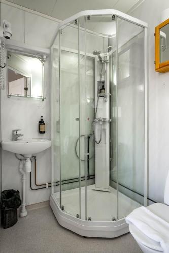 a glass shower in a bathroom with a sink at Mary-Ann's Polarrigg in Longyearbyen