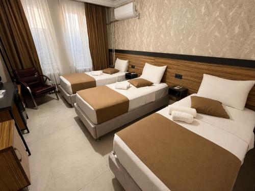 a hotel room with two beds and a chair at Hotel Gazi in Gaziantep