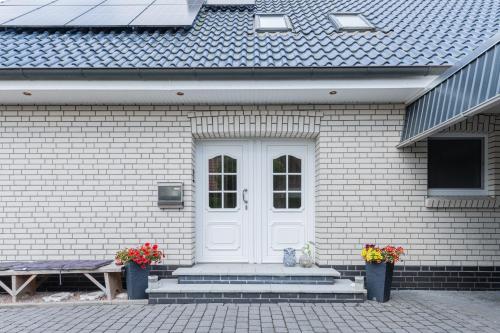 a white door of a house with two potted flowers at Ferienwohnung Am Walde 35177 in Hesel