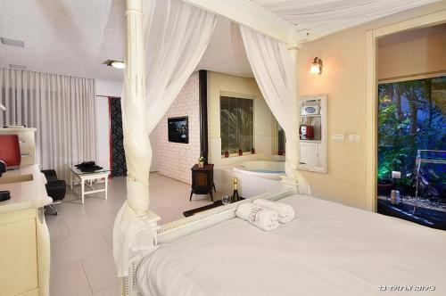 a bedroom with a bed and a bathtub and a bed and a bathroom at סיקרט נס ספא in Had Nes