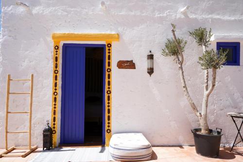 a blue and yellow door in a white wall at Riad Dar Sarah in Taghazout