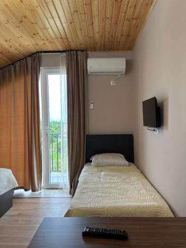 a bedroom with a bed and a window with a television at Corner house in Kobuleti